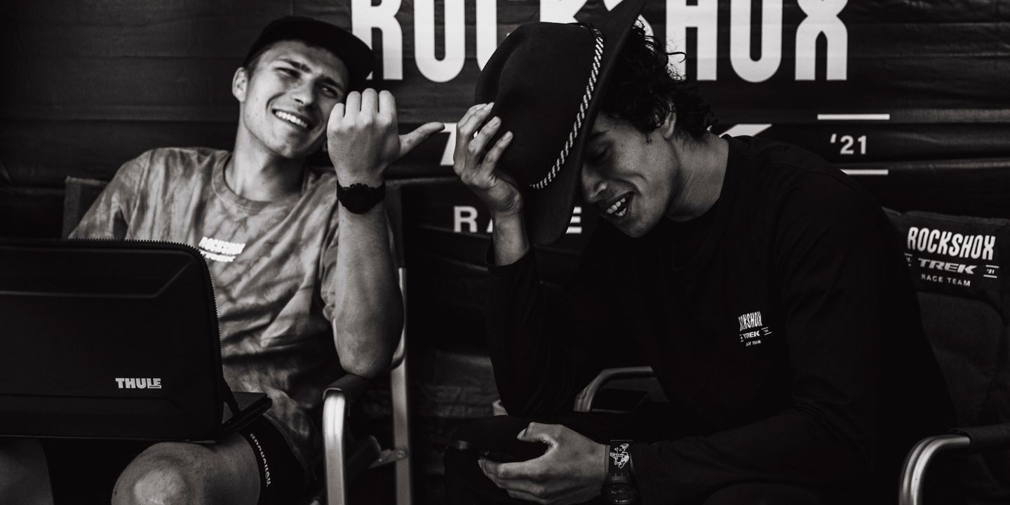 A black and white photo of Kuba Gzela and Tegan Cruz laughing and looking at a phone.