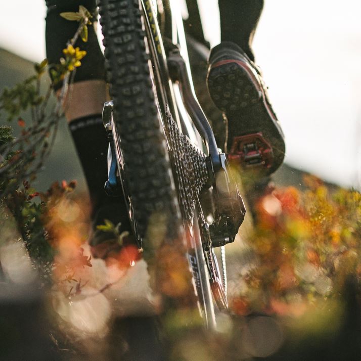 Photography of a Eagle Transmission derailleur and cassette mid-berm, spraying dirt.