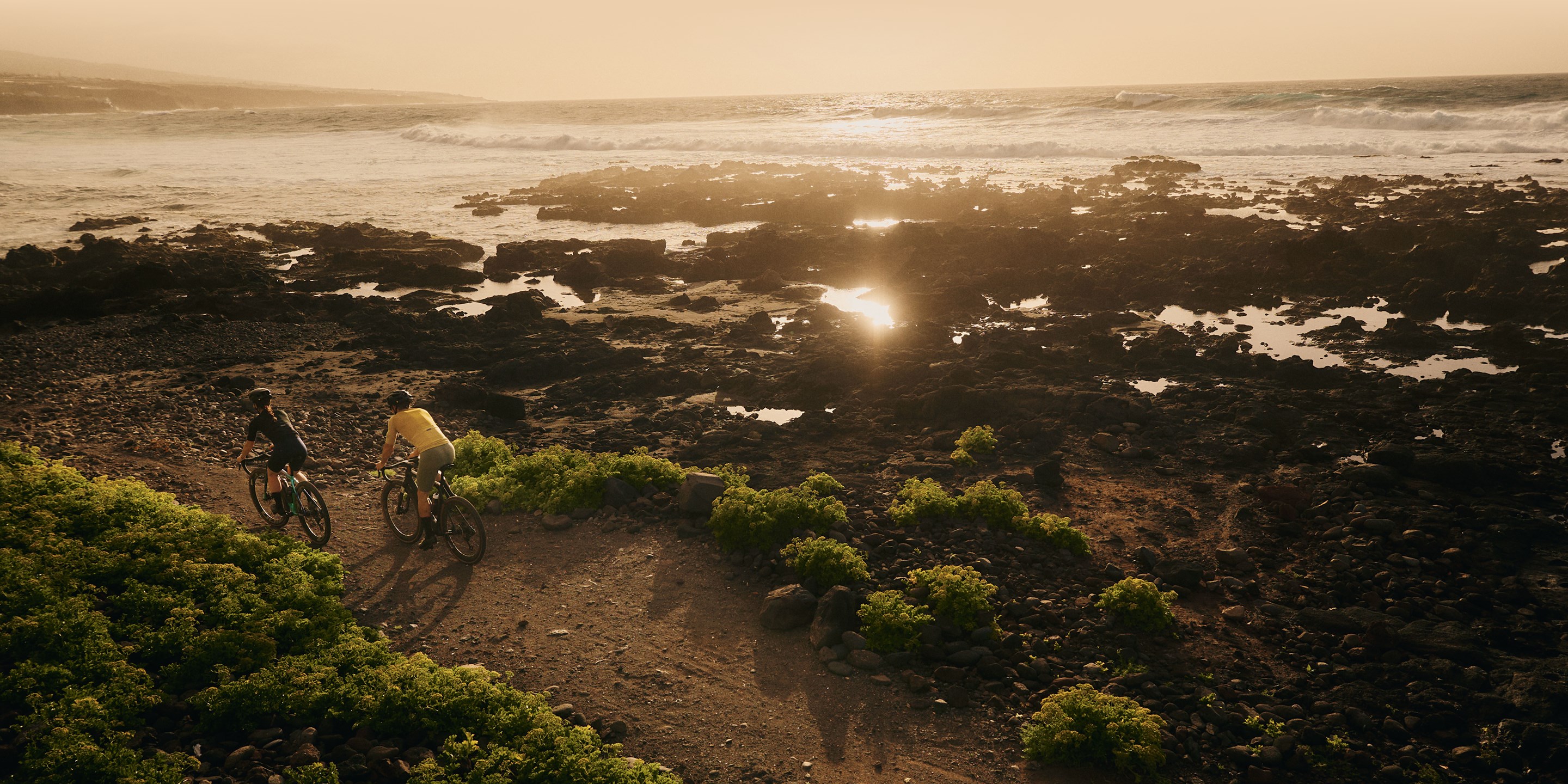 Two SRAM XPLR gravel riders riding into beach sunset