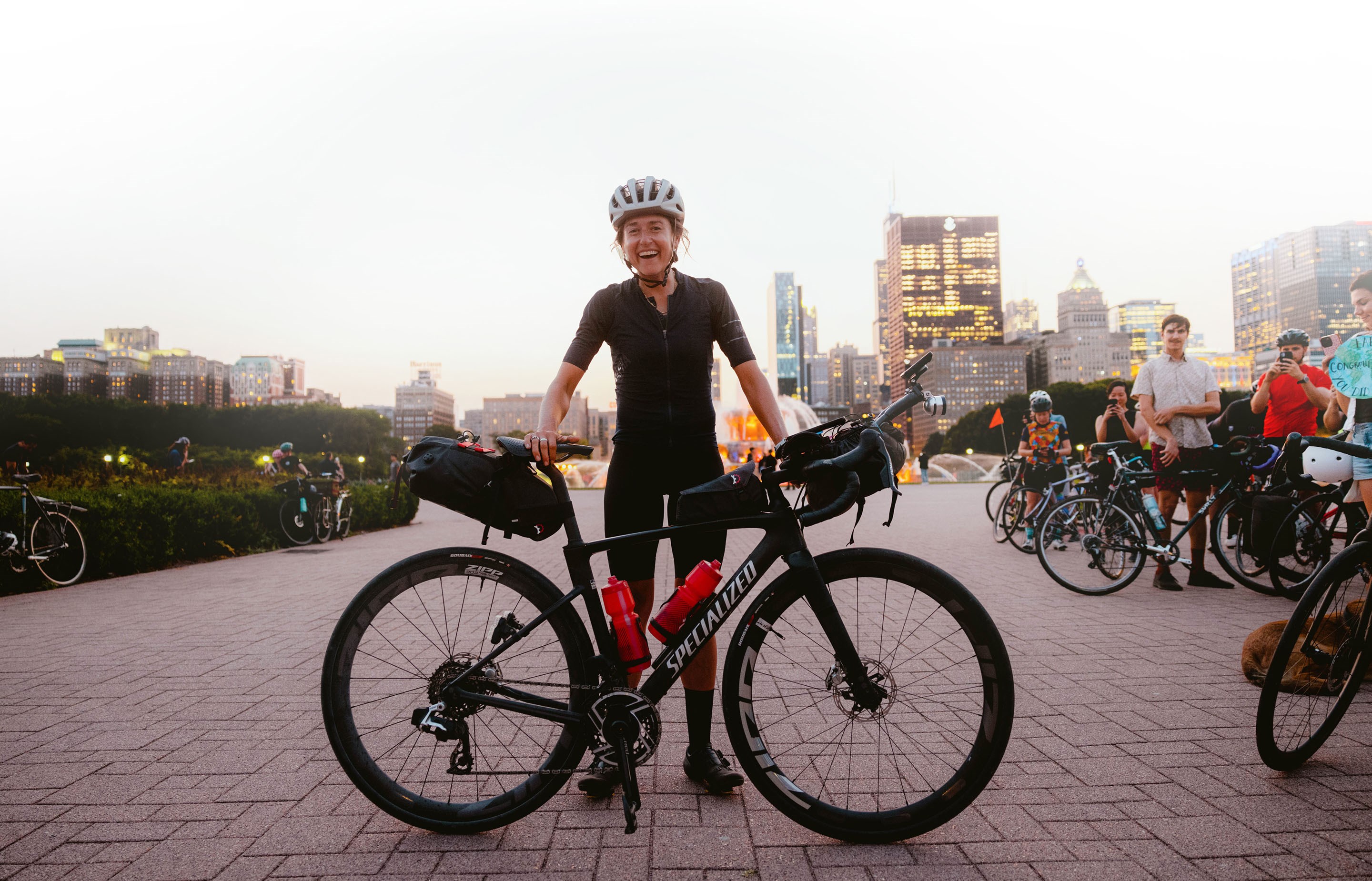 Lael Wilcox standing with her bike at the end of her world record ride.
