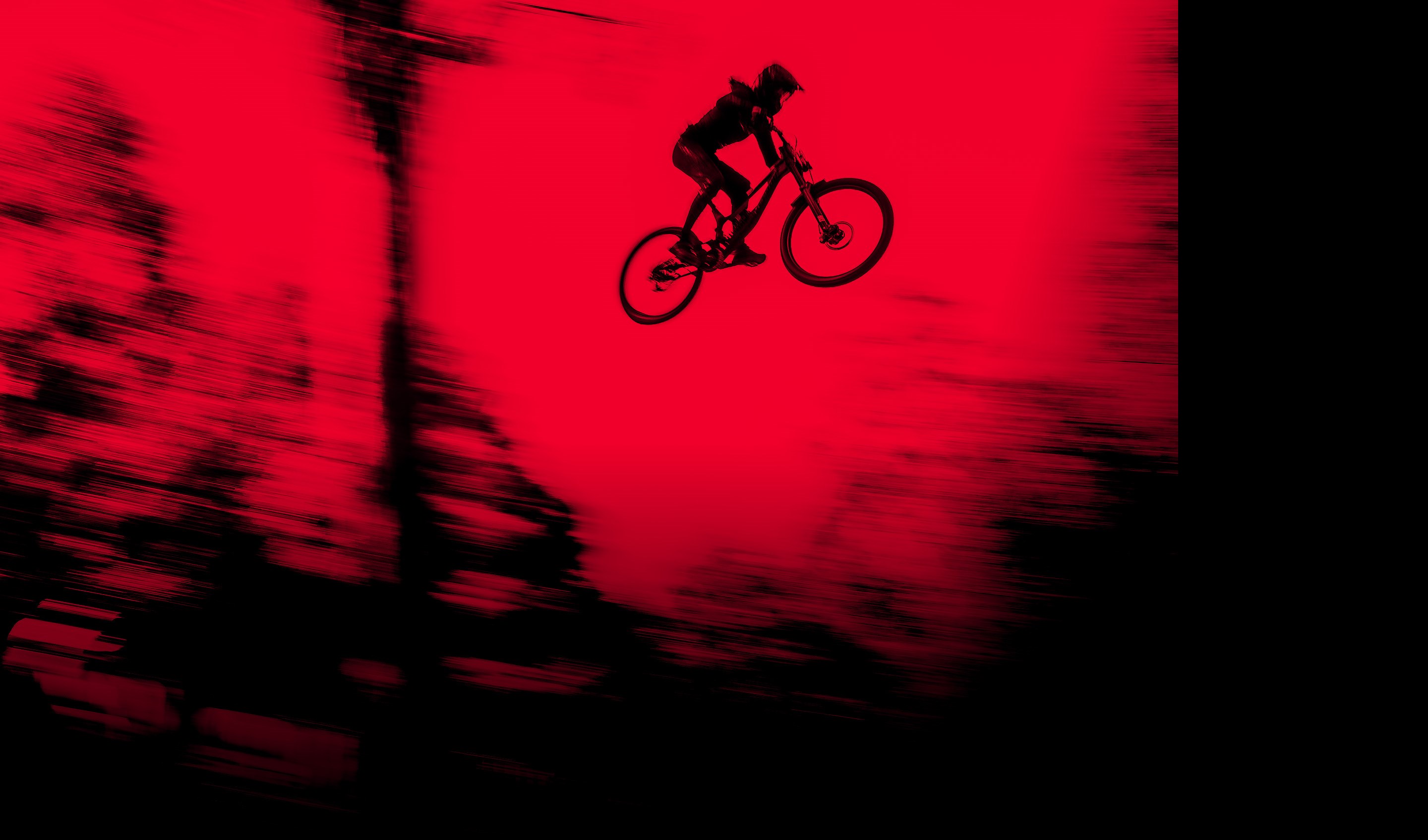 Red tinted image of a DH rider on Boxxer Ultimate and Vivid Coild Suspension.