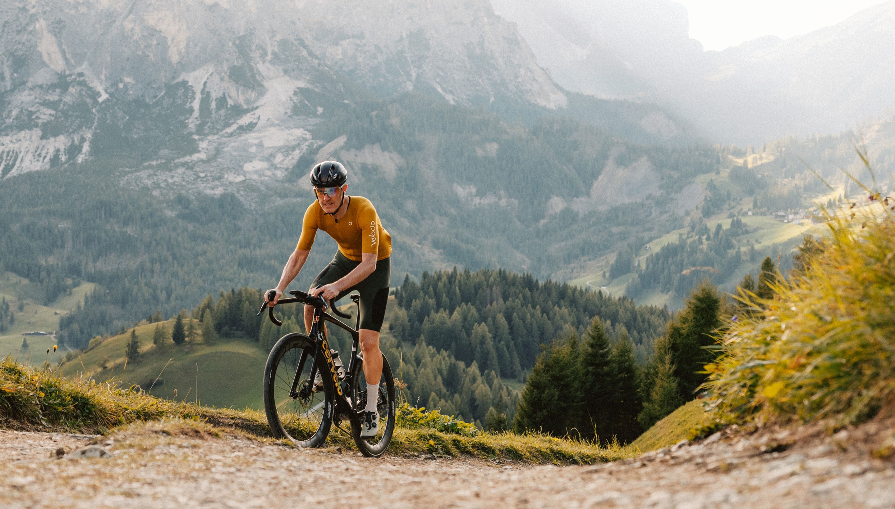 Male Rider on 303SW XPLR wheels climbing a steep gravel road in the mountains.