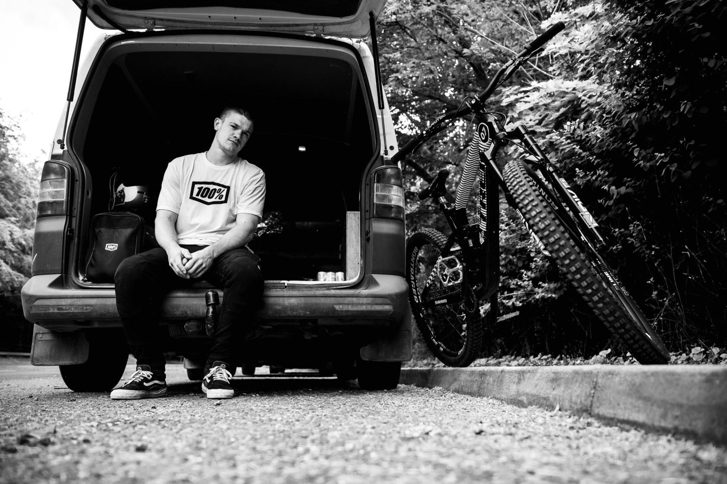 A black and white portrait of Kade Edwards sitting in the back of his van.