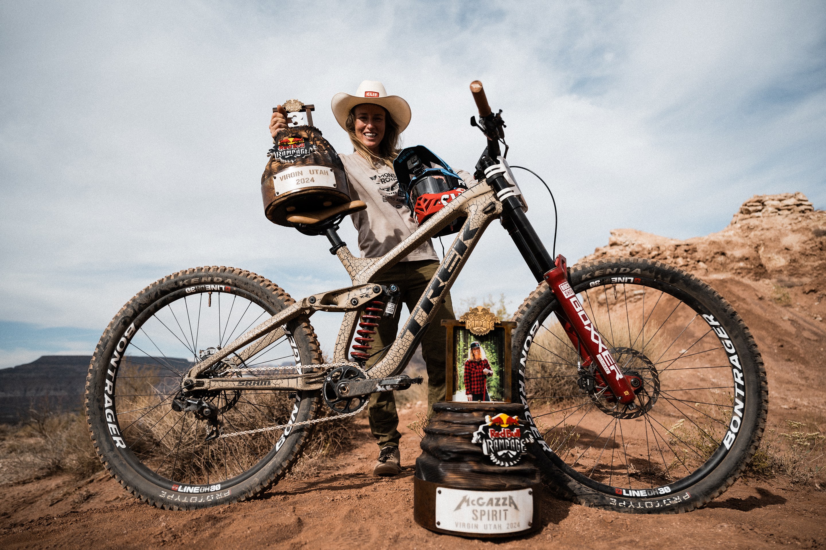Casey Brown posing with her Trek Session and trophies from Red Bull Rampage including the McGazza Spirit Award.