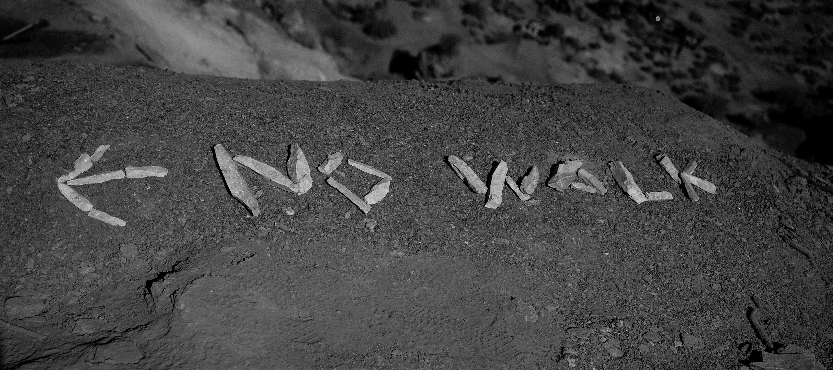 A Black & White photo of "No Walk" written in stones.