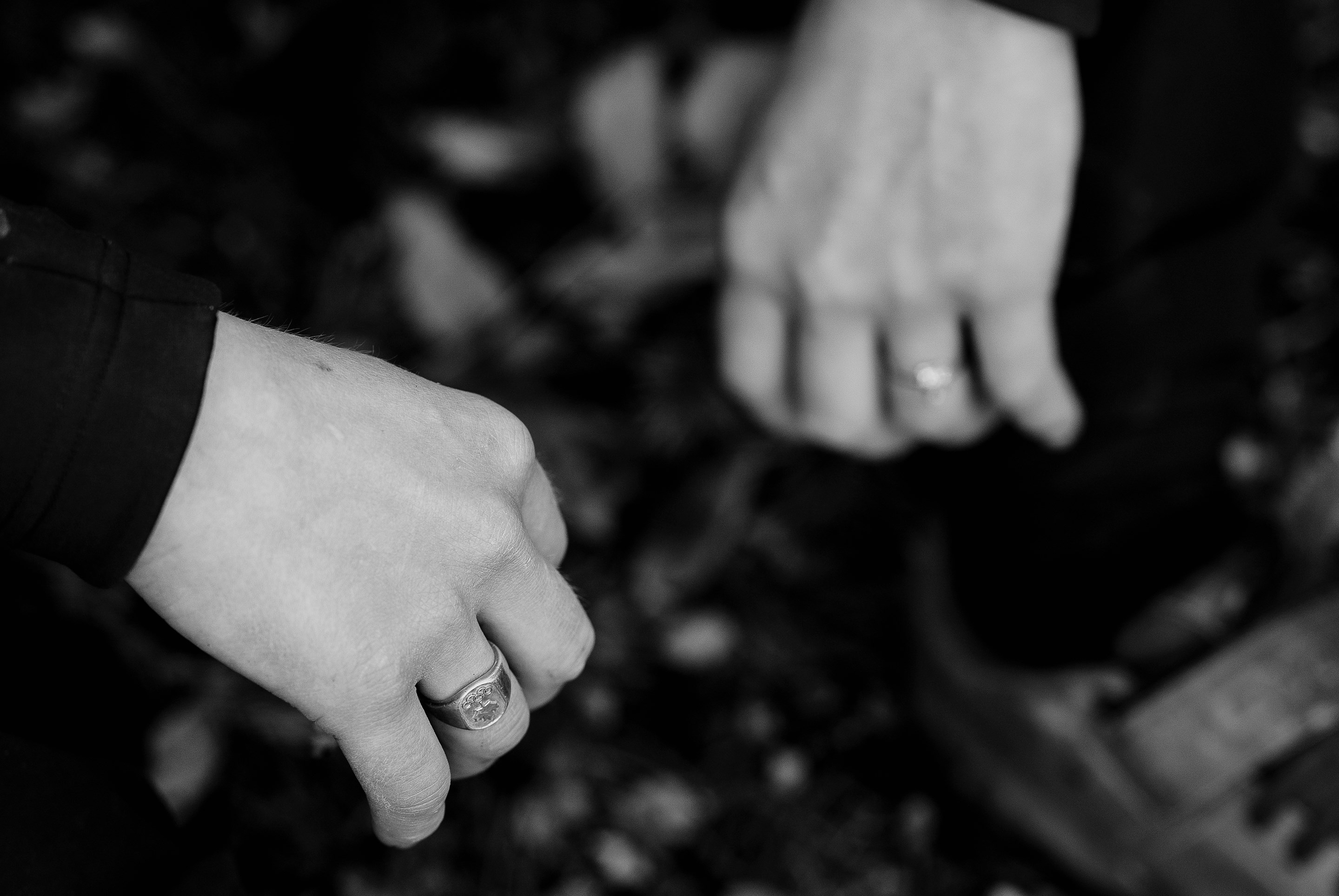 A B&W portrait of Britt Phelan's hands tying her mountain bike shoes with her Olympics ring in focus.