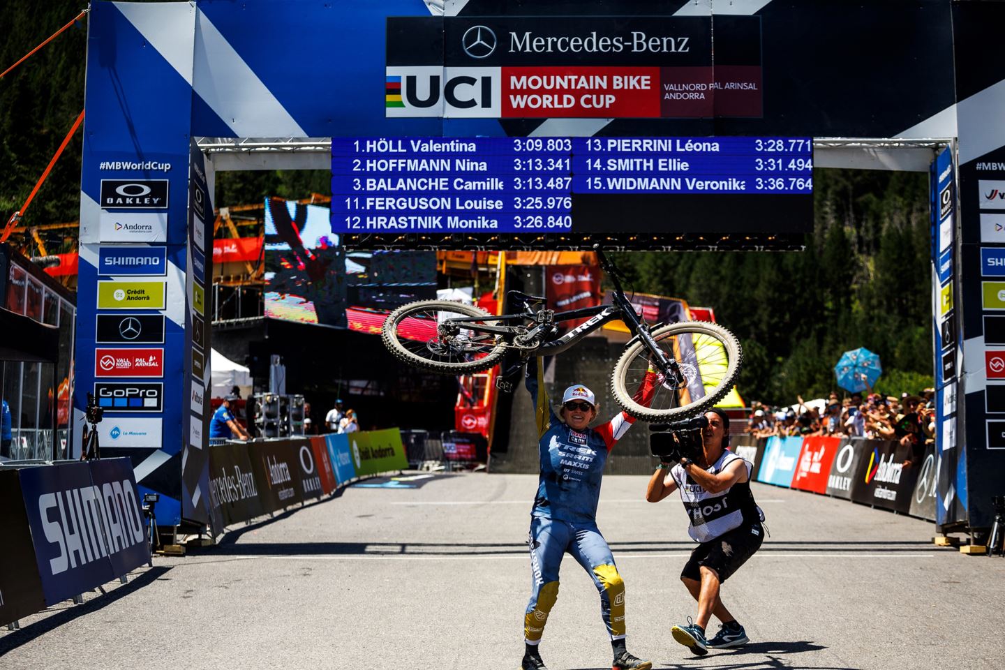 Vali Höll holding her bike over her head in the finish corral in Vallnord, Andorra.