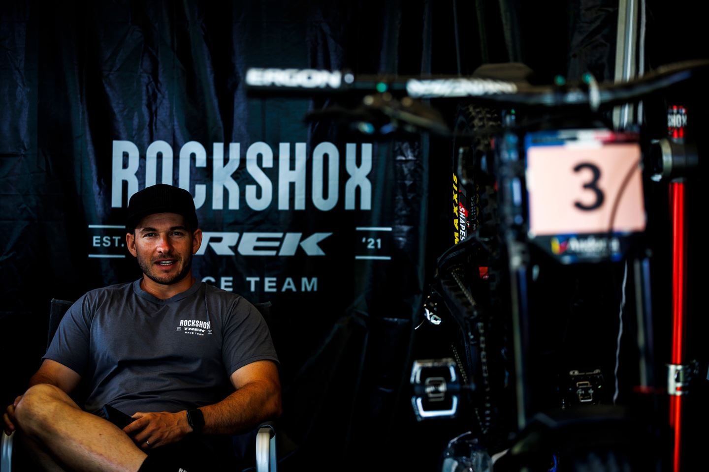 Vali Höll's mechanic, Mat Gallean sitting in front of her bike in the RockShox Trek Race Team pits.