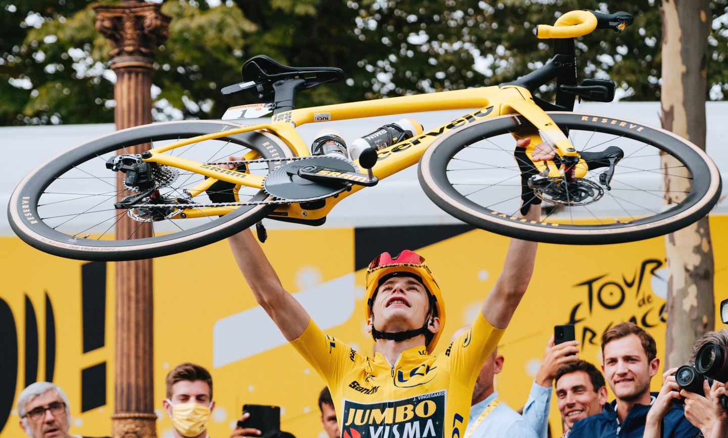 Jonas Vingegaard lifts his bike over his head after winning the men's Tour de France.
