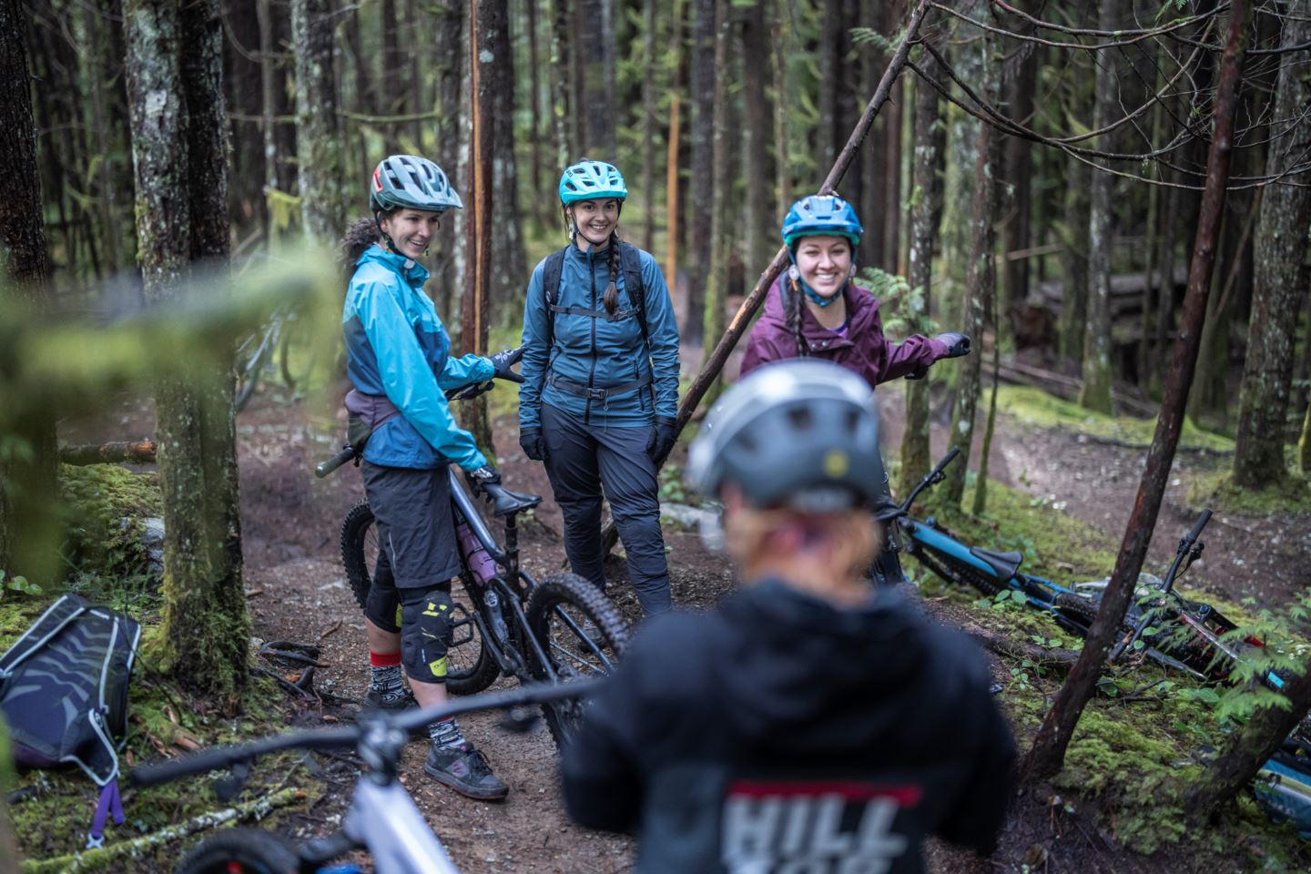 A group of riders talks in the woods