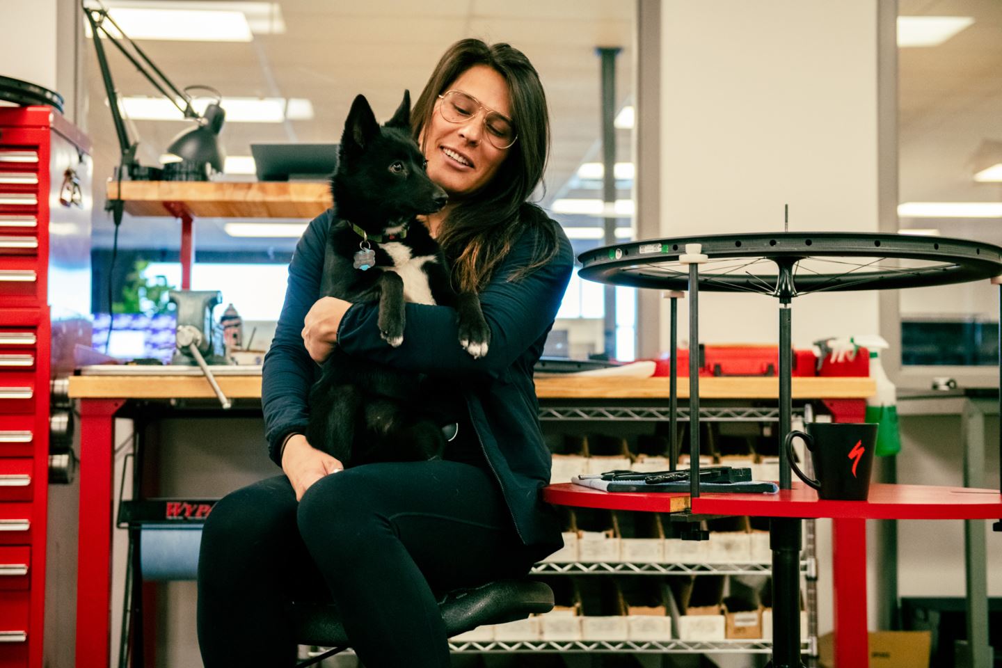 Garrin Evans holding her puppy at Specialized Bicycles near a wheel stand.