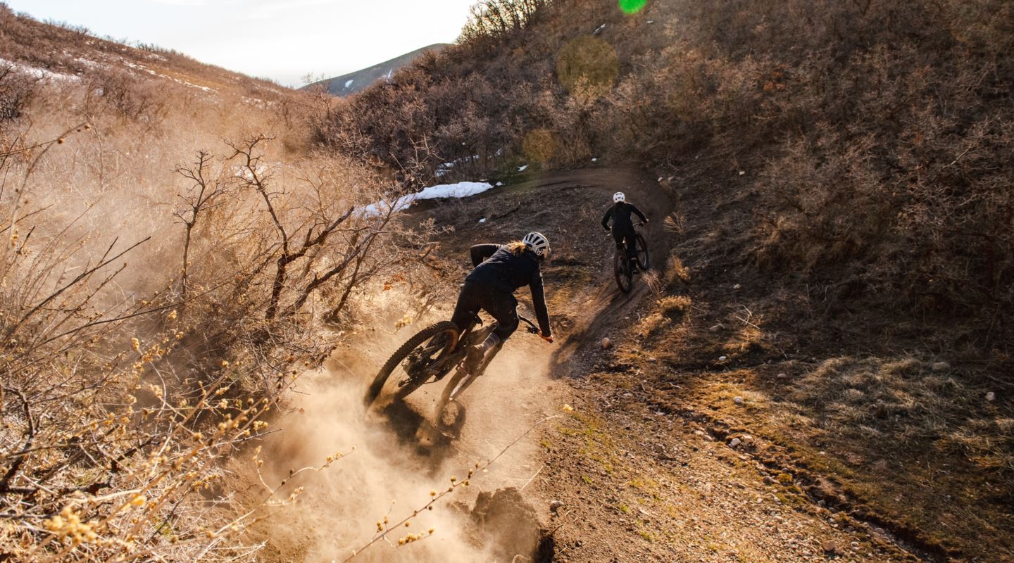 Garrin Evans and Blake Hansen riding a berm with dust in the air.