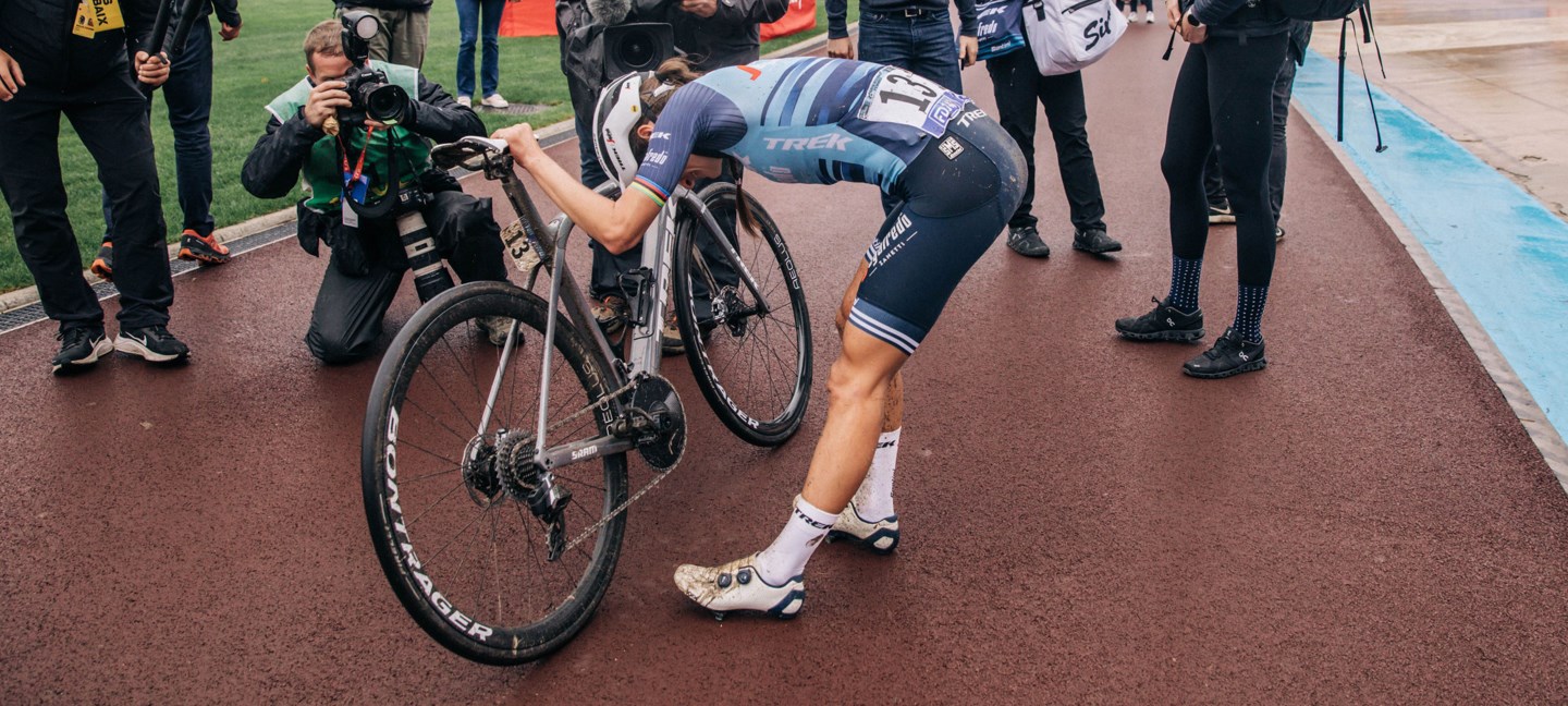 Lizzie Deignan bends over in exhaustion at the side of the track.