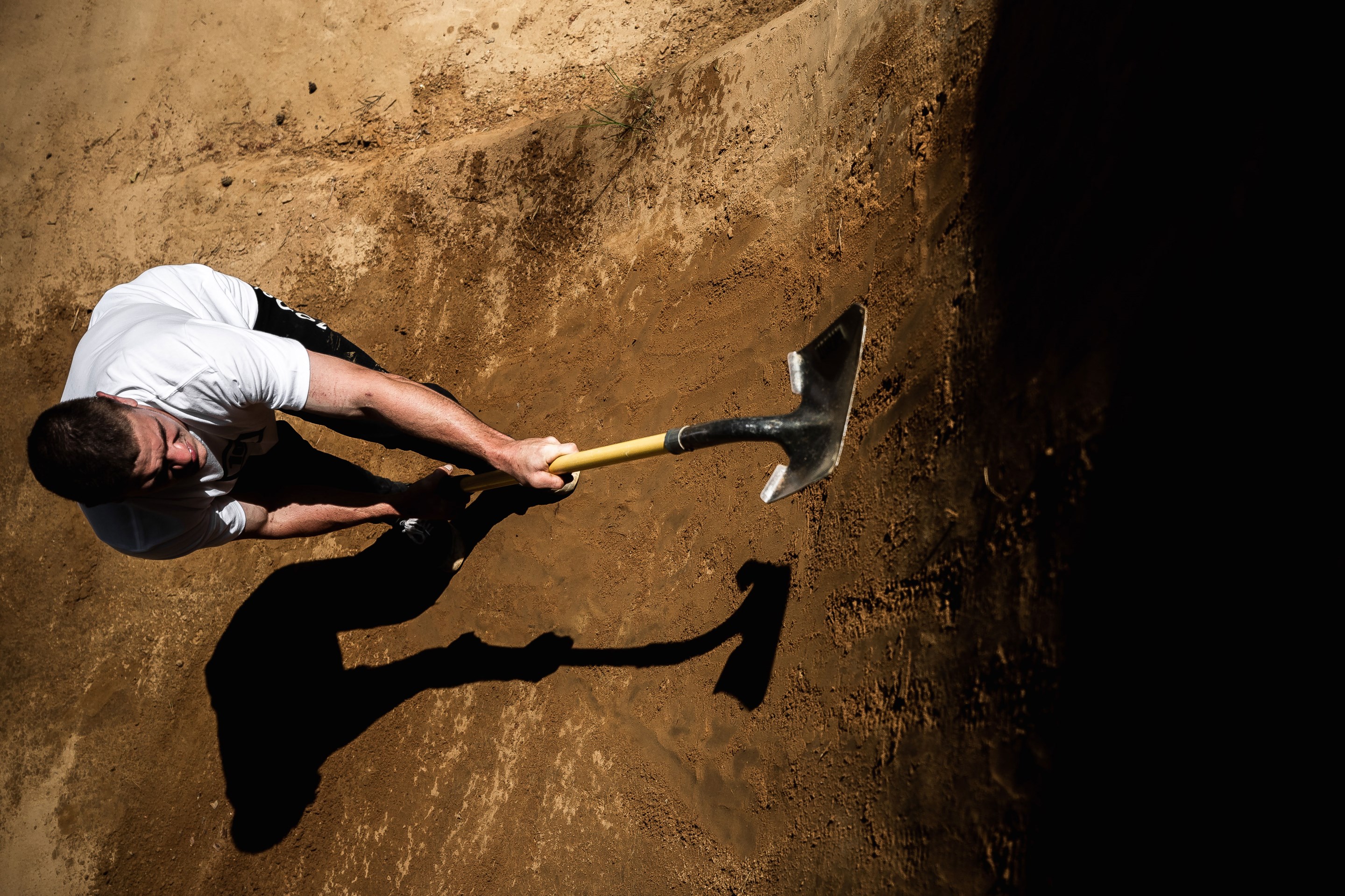 Kade Edwards smoothing out the lip on a dirt jump with a shovel.