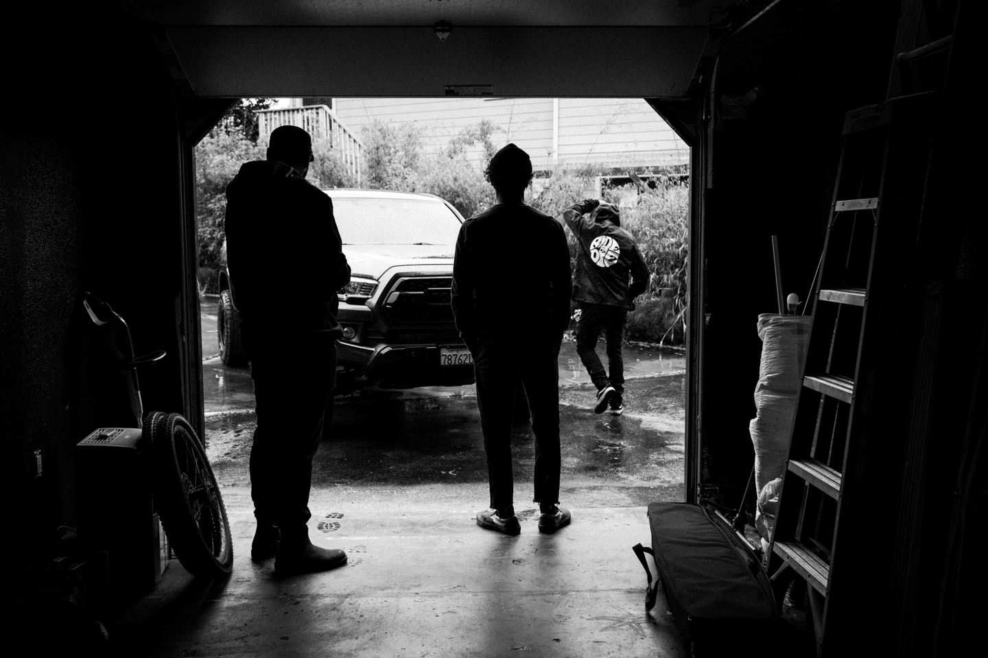 Backlit black and white image of Nic Genovese, Isaac Wallenn and Ryan Howard figuring out what to do on a rainy day.