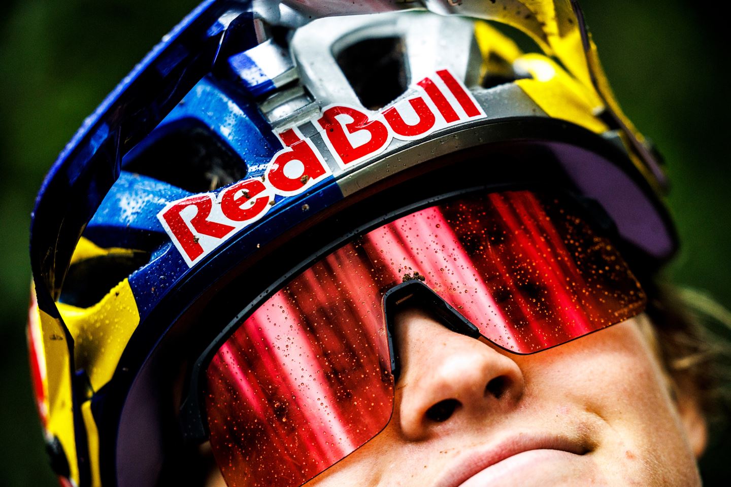 Close-up shot of Vali Höll smiling in the rain wearing her Red Bull helmet.