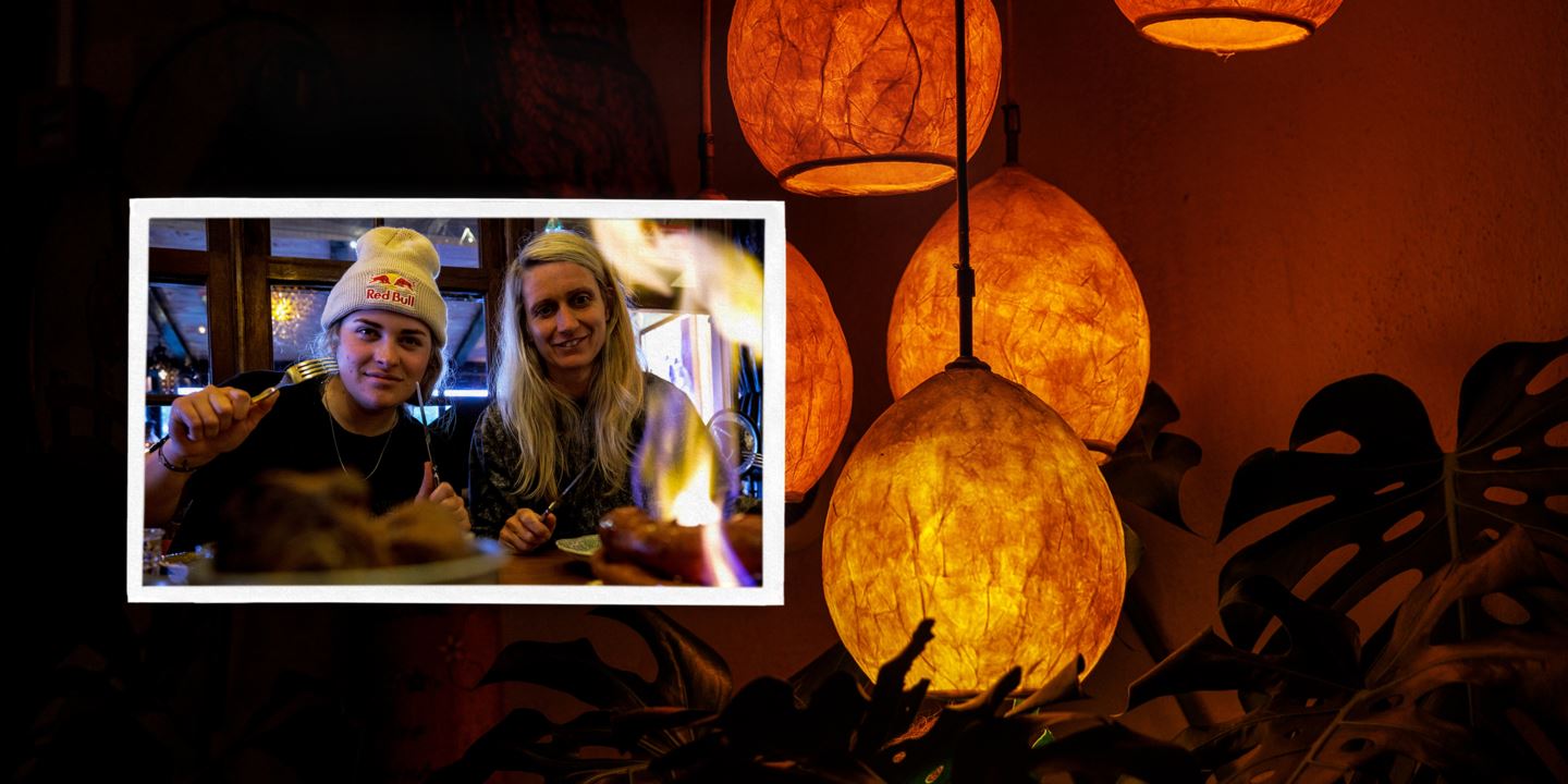 (Picture) Vali Höll and Cécile Ravanel at dinner. (Background) Lanterns hanging in ambient light.
