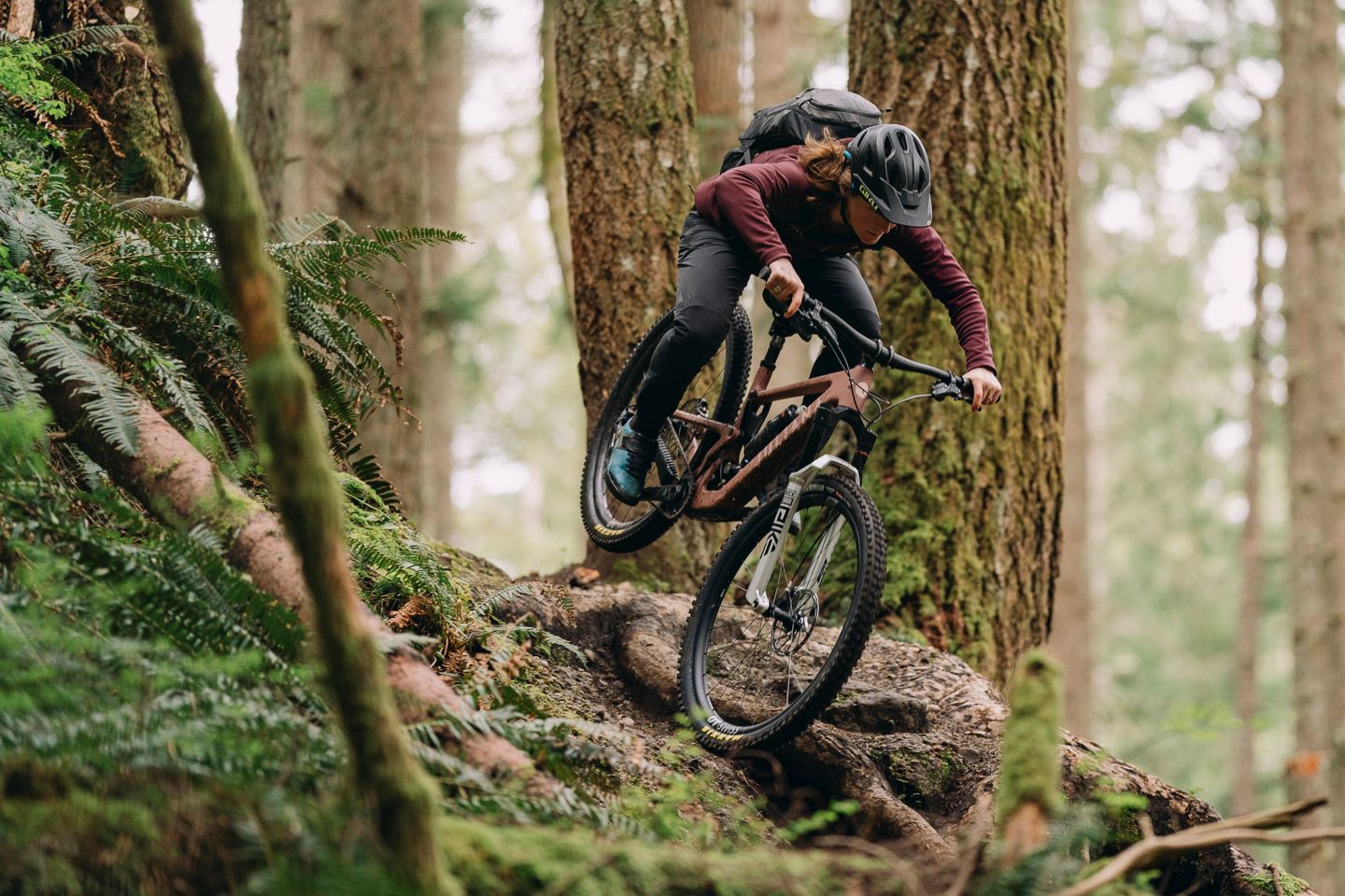 Female mountain biker charging down roots on  bike with a Pike Ultimate fork with Charger 3 damper.