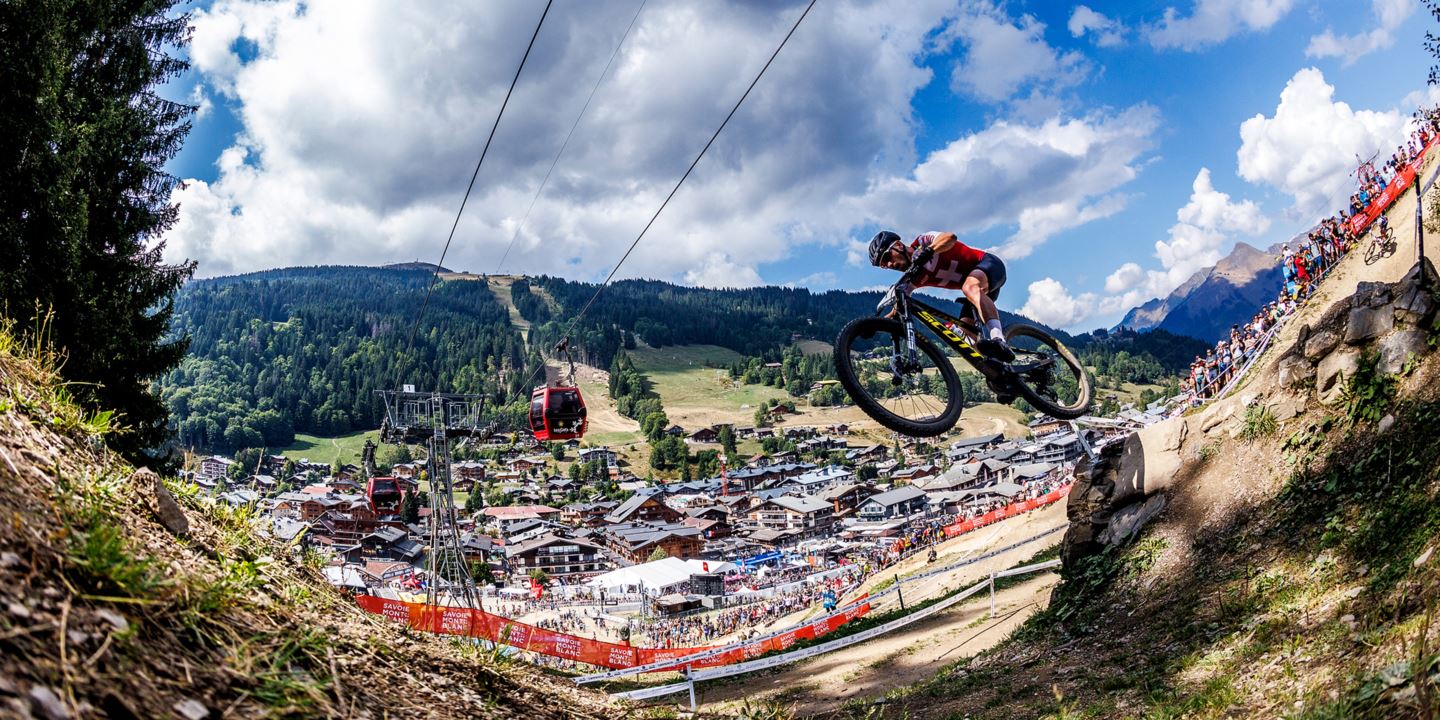 Nino Schurter flying in the air on course during the Elite Men's XCO finals in Les Gets, France.