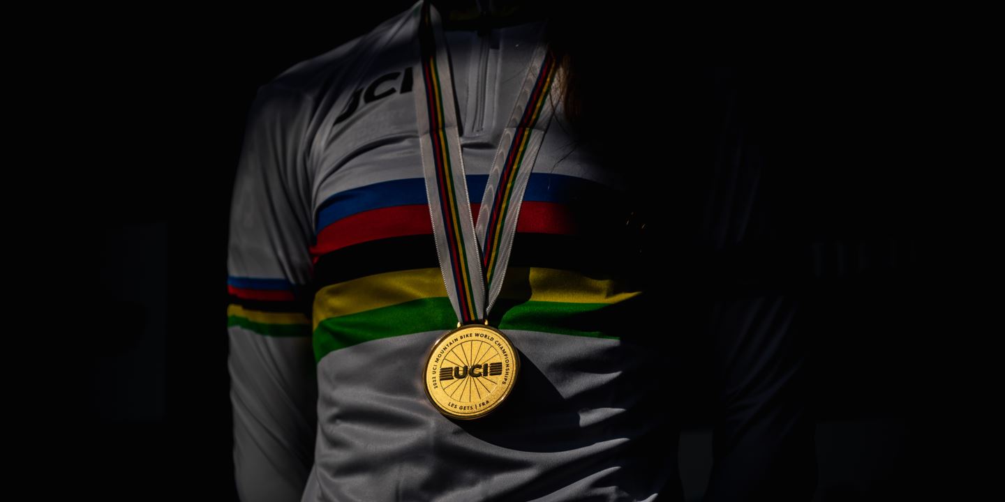 A UCI World Championship medal hanging on the neck of Pauline Ferrand-Prévot in a World Champion jersey.