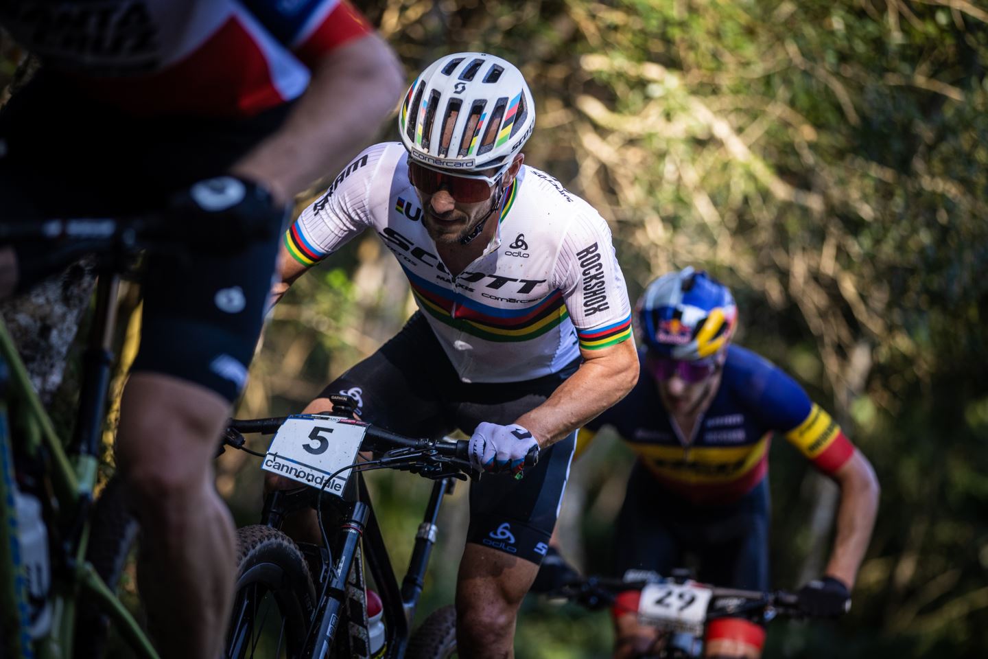 Nino Schurter riding between two riders mid-race in Petrópolis, Brazil.