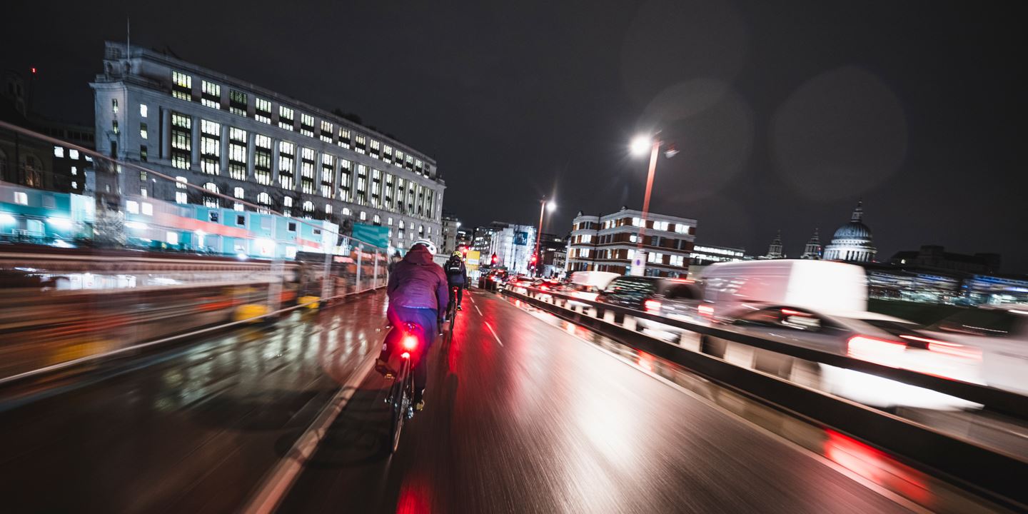 Rachael Walker riding her gravel bike through the city at night with lots of bright lights.