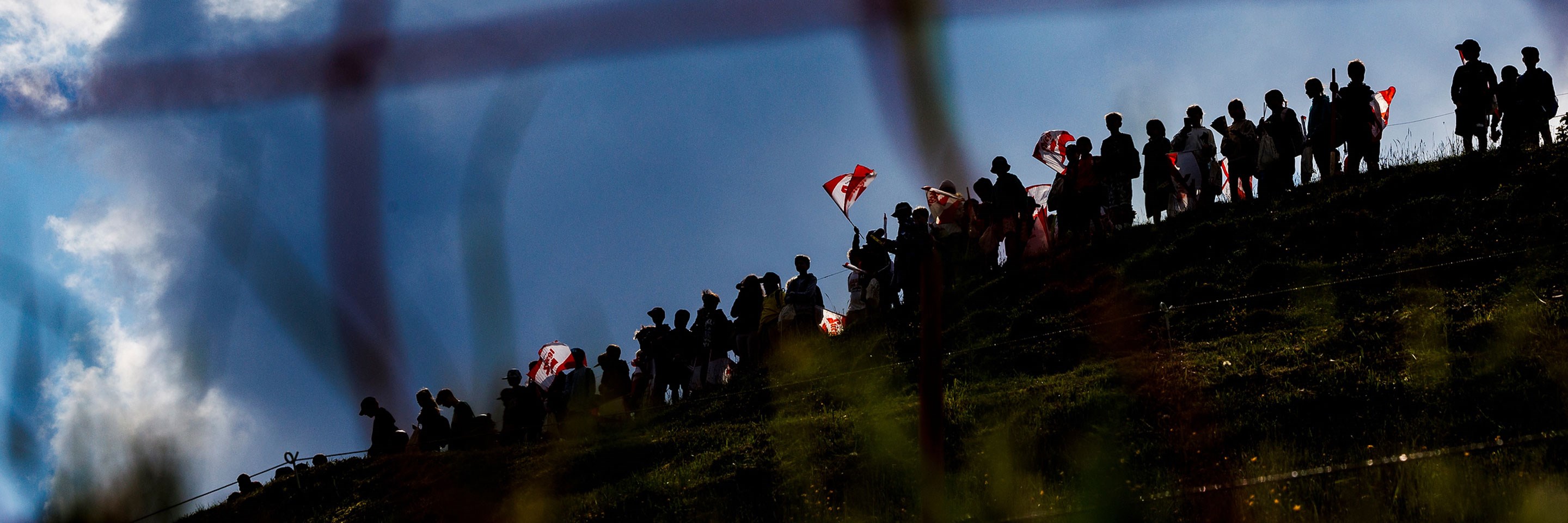 A moody shot of spectators on course at the Leogang DH track through the lens of the B netting.