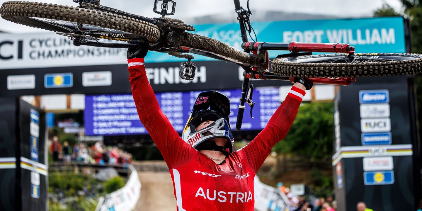 Vali Höll holding her bike about her head after winning her second World Championship title in Fort William, Scotland.