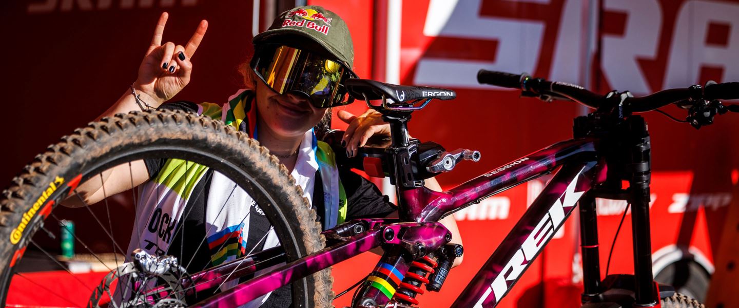 Vali smiling with her favorite Trek Session wearing Oakley goggles and Red Bull baseball cap.