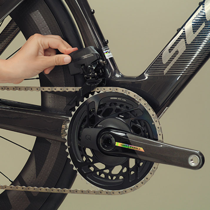 Un cycliste installe une batterie sur un dérailleur avant SRAM Force AXS.