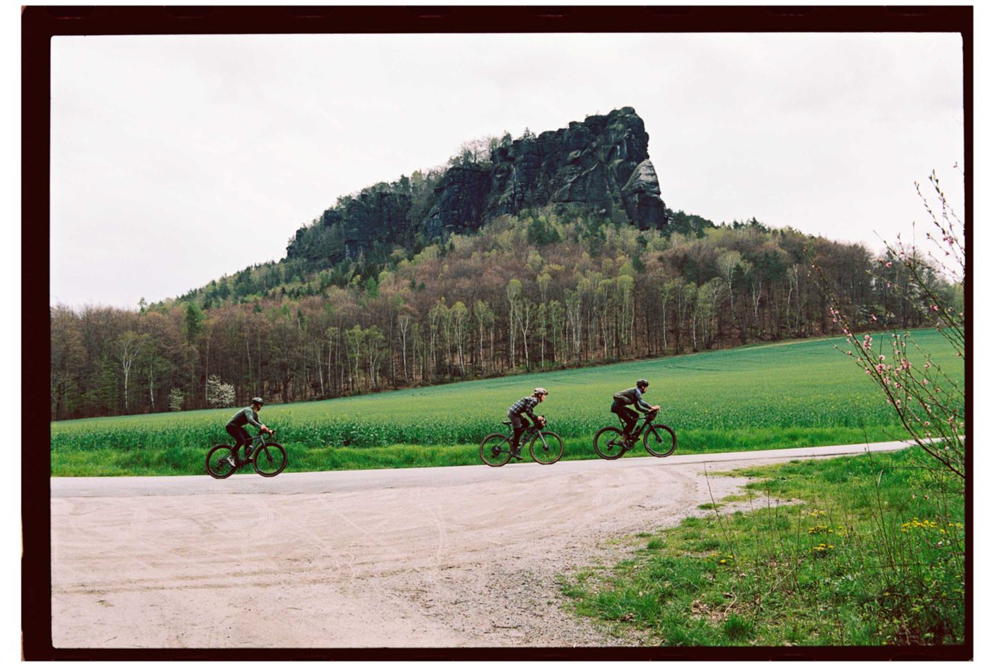 riders pass a large rock outcrop on a gravel ride with SRAM Apex.